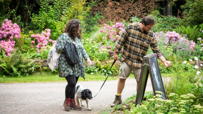 A man and woman with a dog looking at flowers in the cottage garden at Fyne Court